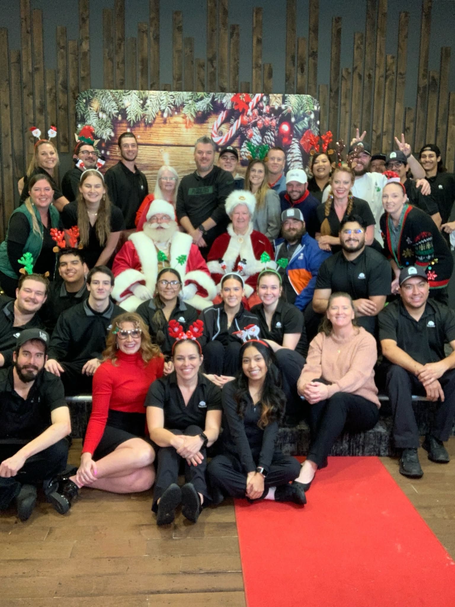 Santa and Mrs. Claus seated at the centre of a large company staff photo, roughly forty people in holiday dress