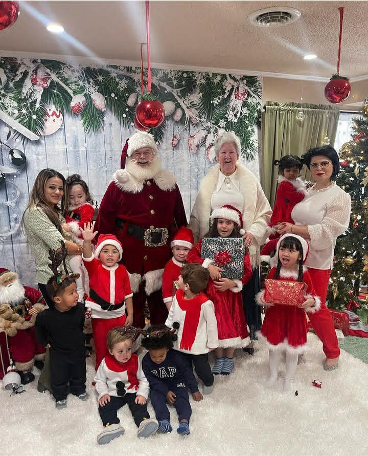 Santa and Mrs. Claus surrounded by a dozen toddlers in matching Santa outfits at a daycare visit